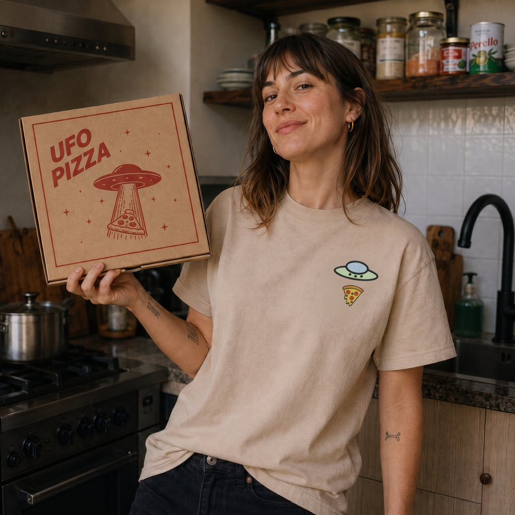 Woman wearing the sand Trees, Rivers & UFOs Forest Pizza Tee in a kitchen.