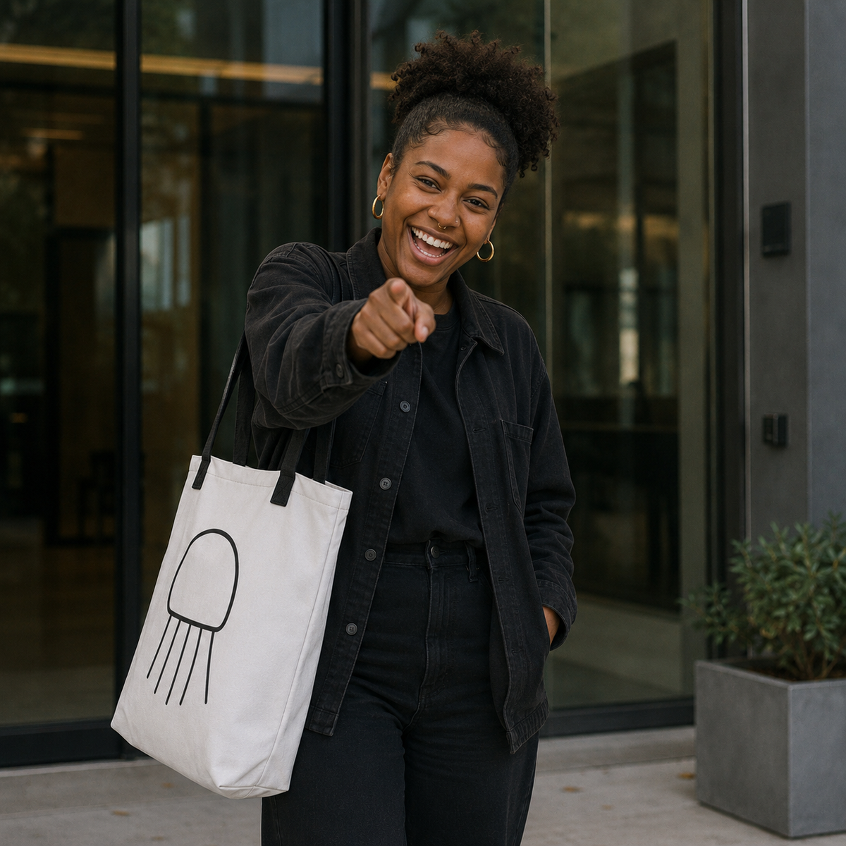 Woman carrying the Trees, Rivers & UFOs Nimbus Jellyfish Tote Bag, a white tote with black straps and monochrome jellyfish artwork with black outline and tentacles.