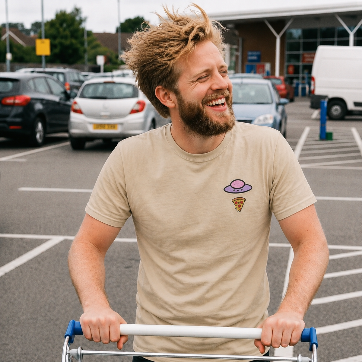 Man wearing the sand Trees, Rivers & UFOs Orchid Pizza Tee while smiling and pushing a shopping cart in a parking lot.