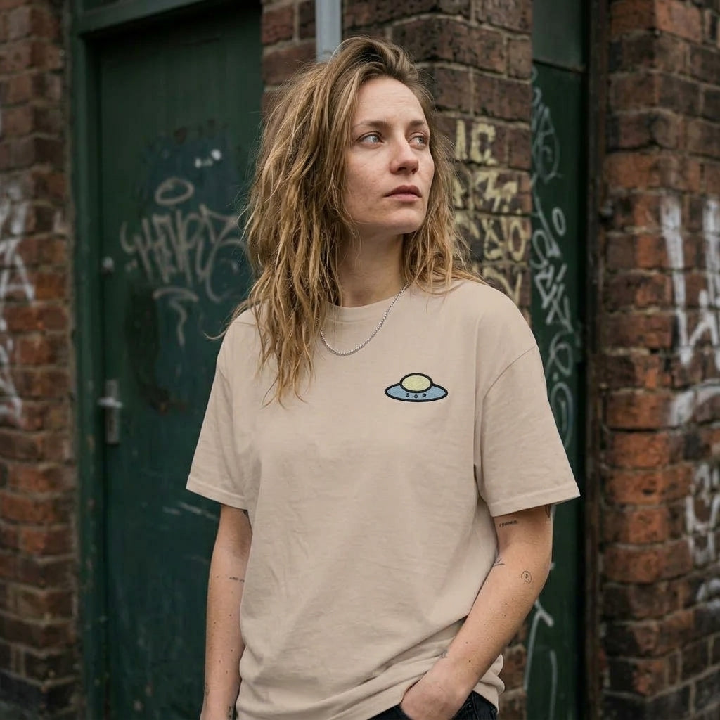 Womennwearing the sandstone Trees, Rivers & UFOs Tee on an urban street with graffiti walls.