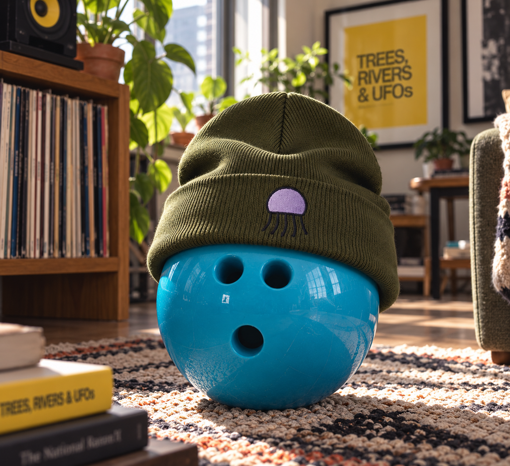 Olive Orchid Beanie with purple Jellyfish embroidery on a blue bowling ball